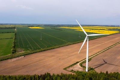Aerial view of a large three blade industrial wind turbine generating electricity in a wind farm