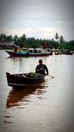 Man in boat on river against sky