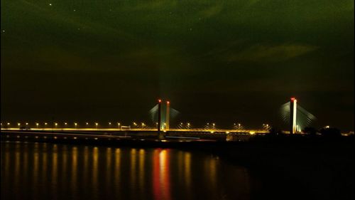 Illuminated bridge over river at night