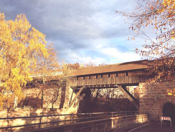 Arch bridge over river against sky during autumn