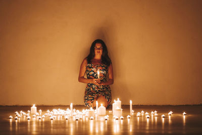 Woman standing by illuminated lighting equipment on table