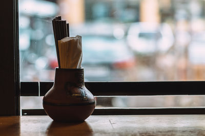 Close-up of chopsticks and napkins in container on table at restaurant