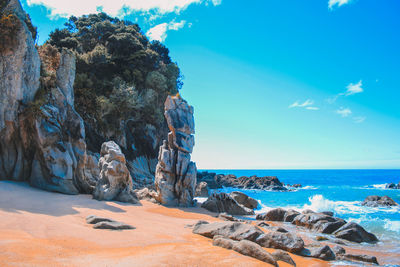 Rock formation on beach against sky