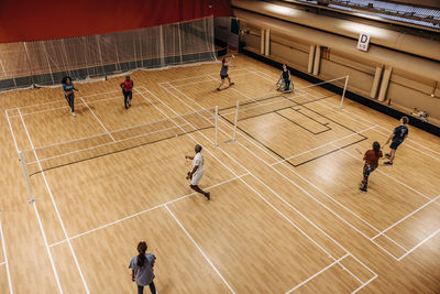 High angle view of male and female athletes playing badminton at sports court