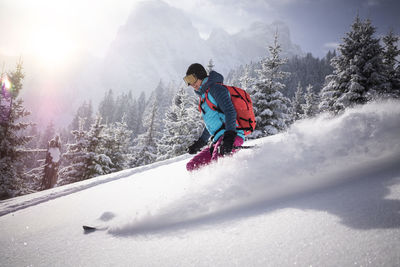 Female skier skiing on snowy mountain during sunny day