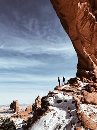 People standing on rock against sky