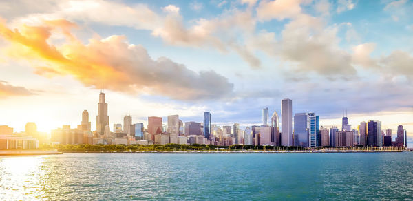 Sea by modern buildings against sky in city