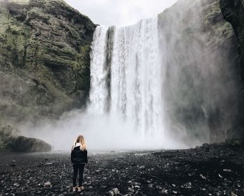 Rear view of young woman looking at waterfall