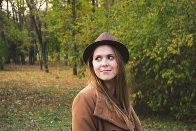 Portrait of beautiful young woman standing against plants