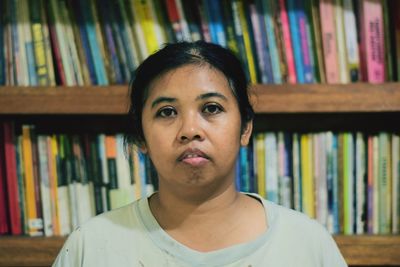 Portrait of woman against bookshelf in library