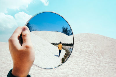 Man holding umbrella on land against sky