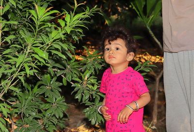 Cute girl standing amidst pink plants