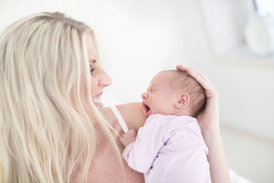 Woman holding yawning newborn daughter