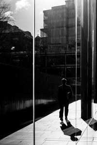 Reflection of man walking on street 