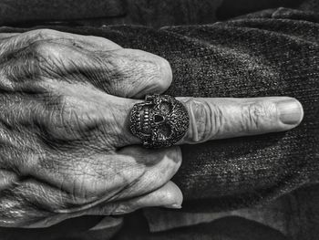 Cropped hand with skull ring showing obscene gesture