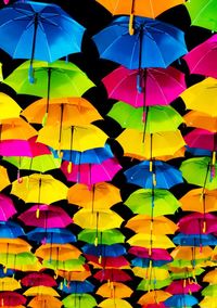 Full frame shot of colorful umbrellas hanging against black background