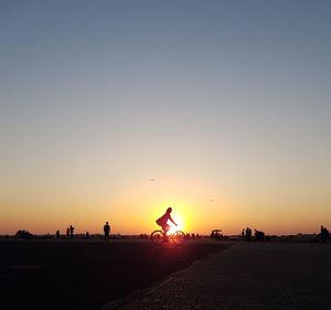 Silhouette person by road against clear sky during sunset