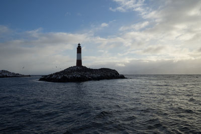 Lighthouse by sea against sky