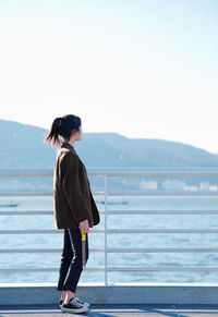 Full length of woman standing by railing against sky