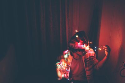 High angle view of man with illuminated string lights at home