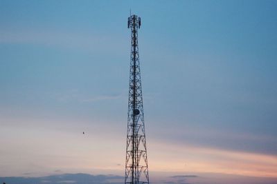 Low angle view of telecommunications tower against cloudy sky during sunset