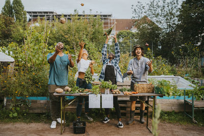 Cheerful male and female environmentalists throwing vegetables in farmer's market