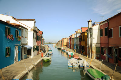 Boats moored in canal amidst buildings in city against sky