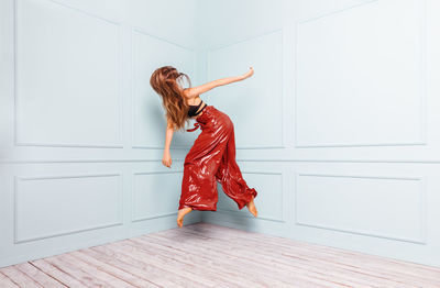 Anonymous stylish dancer jumping in corner of studio
