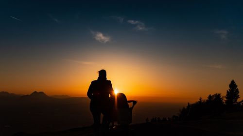 Silhouette men against orange sky during sunset