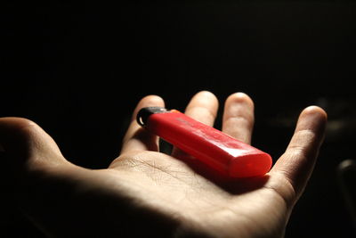 Close-up of person holding hand over black background