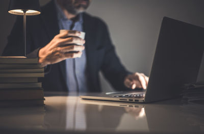 Midsection of businessman using laptop at table