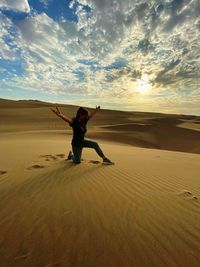 Full length of man on sand dune in desert against sky