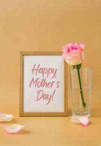 Wooden frame with greeting card text happy mothers day delicate pink roses on beige background