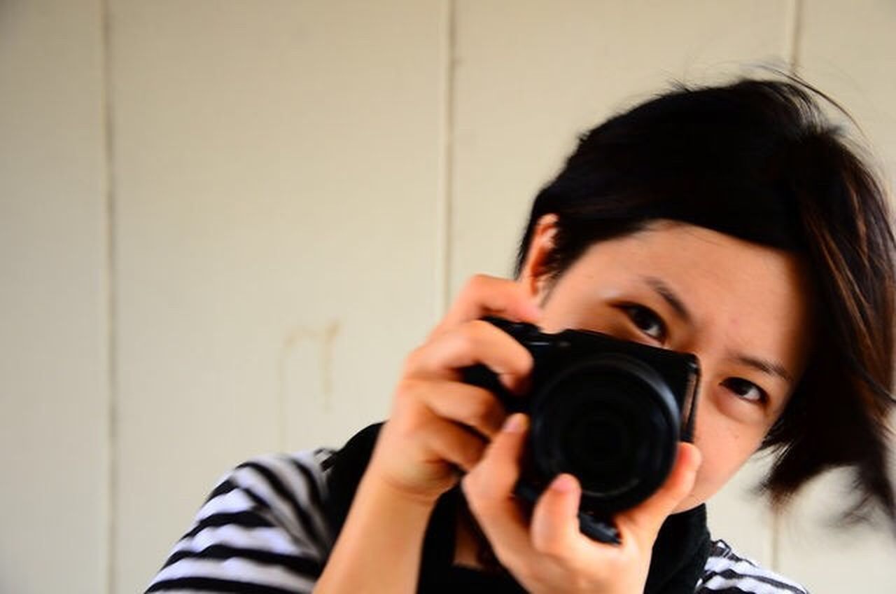 one person, camera - photographic equipment, photography themes, headshot, technology, portrait, holding, photographing, activity, young adult, occupation, casual clothing, adult, photographic equipment, front view, indoors, photographer, digital camera, women, slr camera, teenager, obscured face
