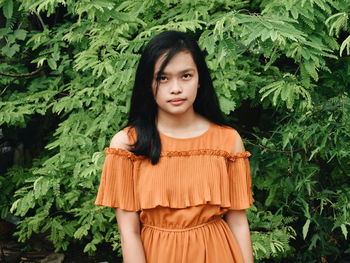 Portrait of beautiful young woman standing against plants