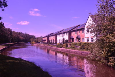 Buildings by river against clear sky