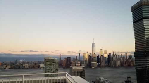 Modern buildings in city against sky during sunset