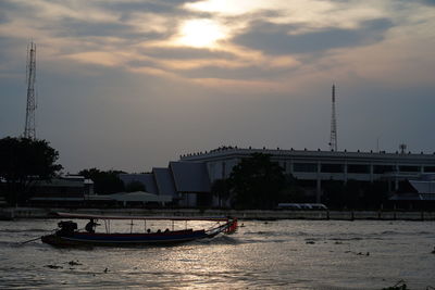 Sailboats moored on river against sky at sunset