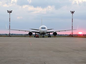 Airplane at airport runway against sky