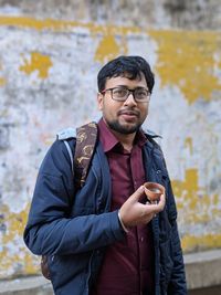 Young man using mobile phone against wall