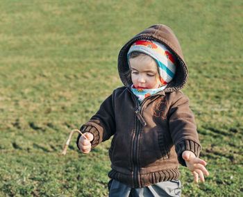 Girl holding stick while standing on grassy field