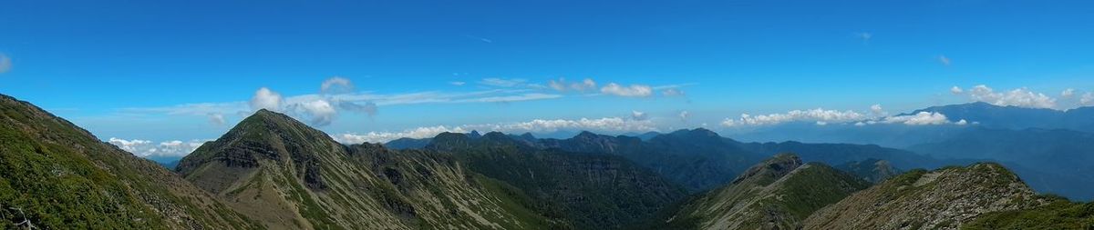 Panoramic view of trees and mountains against blue sky