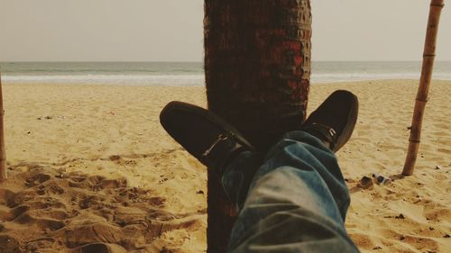 Low section of man relaxing on beach