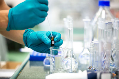 Midsection of scientist holding vial in laboratory