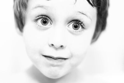 Close-up of cute boy with raised eyebrows against white background