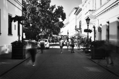 People walking on street amidst buildings in city