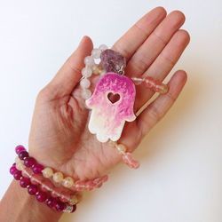 Close-up of hand holding pink flower over white background