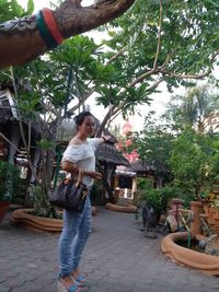 Full length of young woman standing against trees