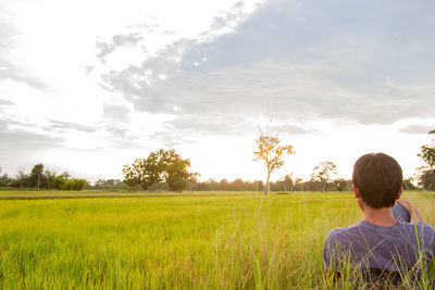 Rear view of man on field against sky