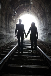 Rear view of silhouette people walking in tunnel